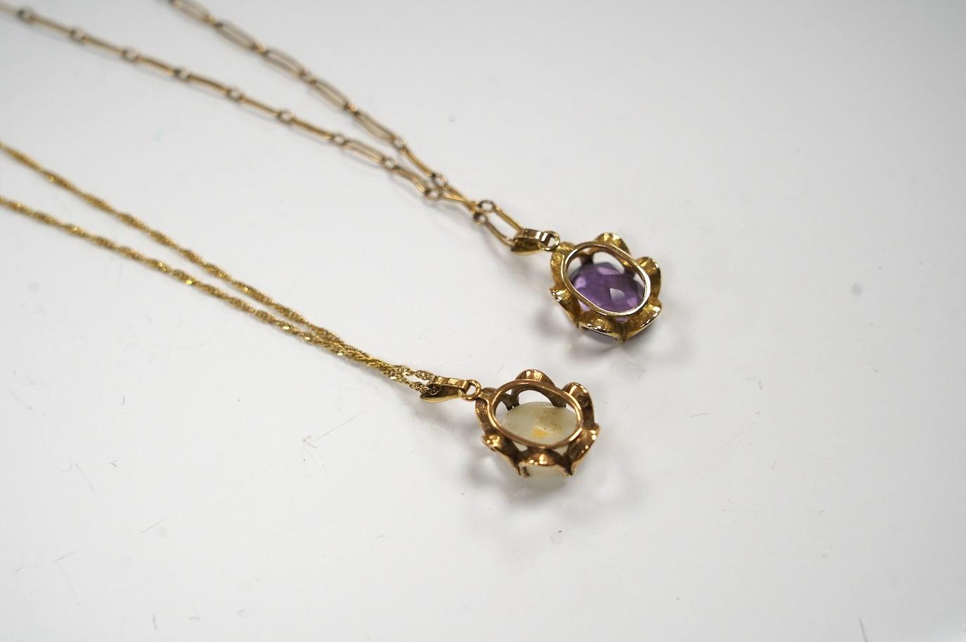 A modern 9ct gold and white opal set pendant, 21mm on a 14k chain, 46cm, gross weight 3.8 grams and a 9ct gold and amethyst set pendant on a yellow metal chain, gross weight 5 grams. Condition - fair